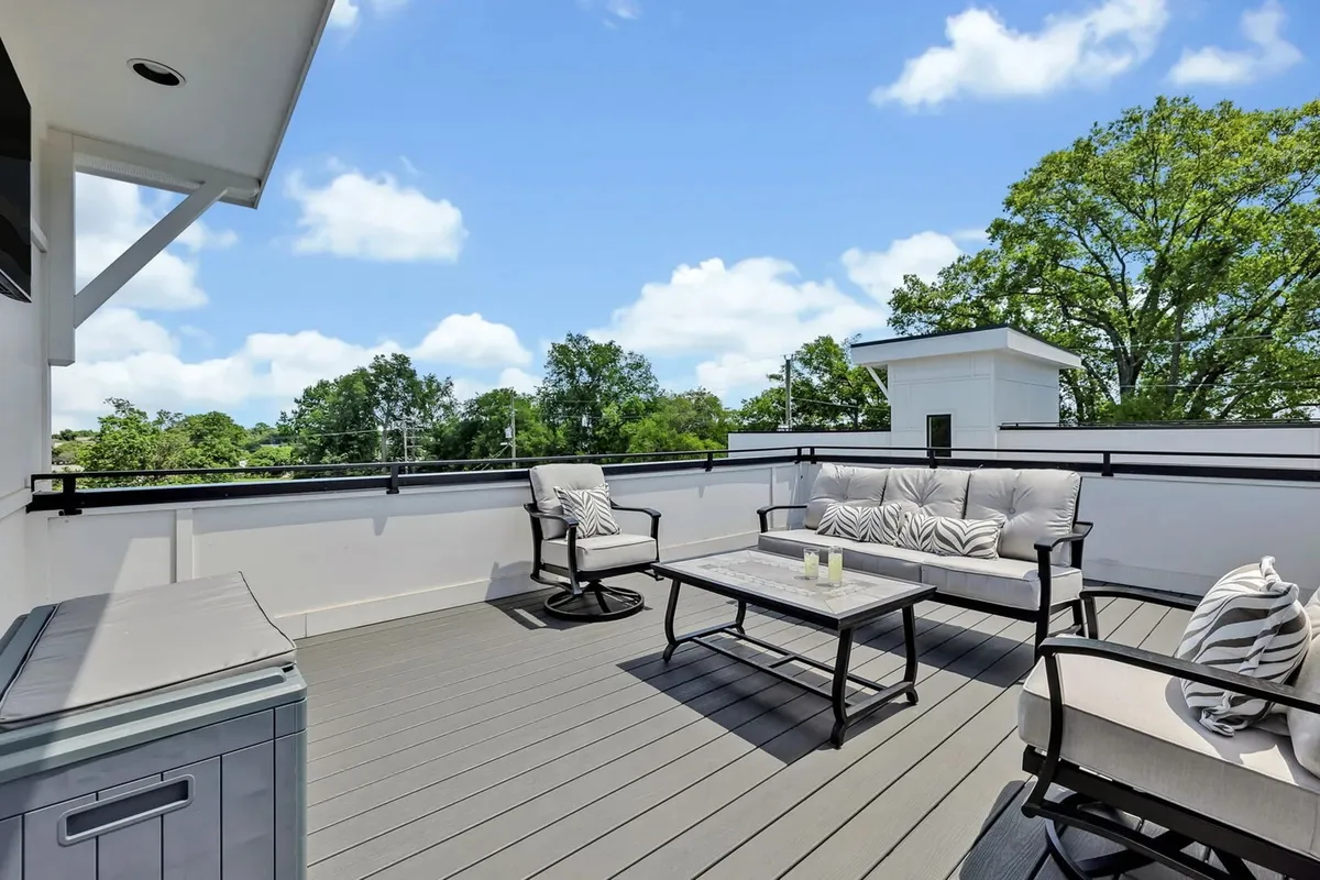 An inviting outdoor seating area with a coffee table overlooks greenery, offering a peaceful setting for entertaining guests or enjoying a morning coffee. The open-air arrangement fosters an atmosphere of relaxation and group interaction.