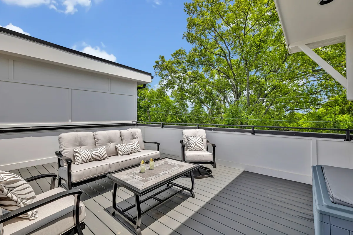 An inviting exterior rooftop patio featuring a comfortable outdoor seating area, a coffee table, and surrounding greenery. The scene radiates serenity and safety, making it perfect for relaxed evenings, stargazing, or family games under the stars.