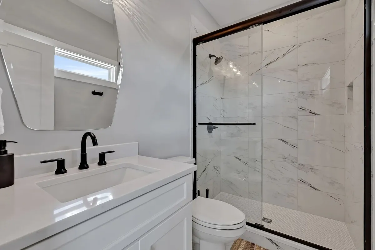 A spa-inspired bathroom with a modern vanity featuring double sinks, a glass-enclosed shower, and sleek fixtures. The space exudes freshness and tranquility, reminiscent of a boutique hotel bath.