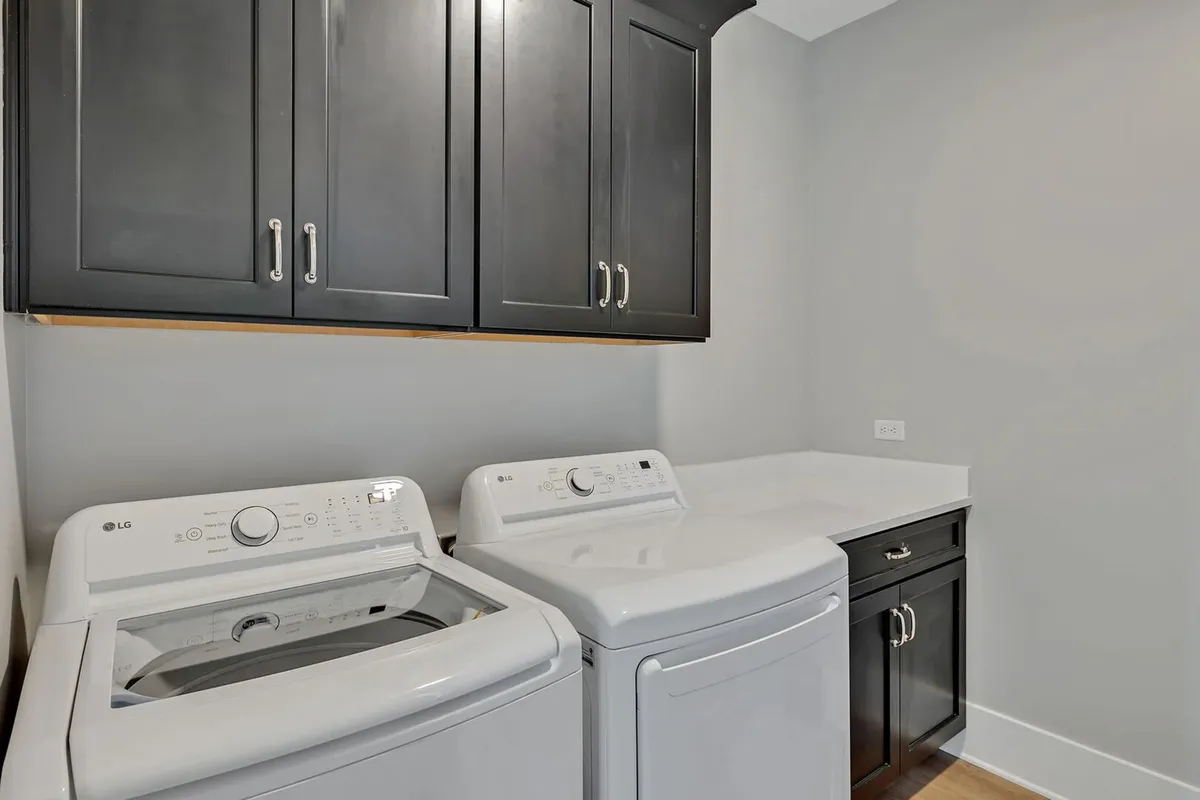 A dedicated laundry area featuring a modern washing machine, dryer, and ample cabinetry for organizing cleaning supplies. The space feels practical, efficient, and well-maintained, hinting at the home's readiness to support daily routines.