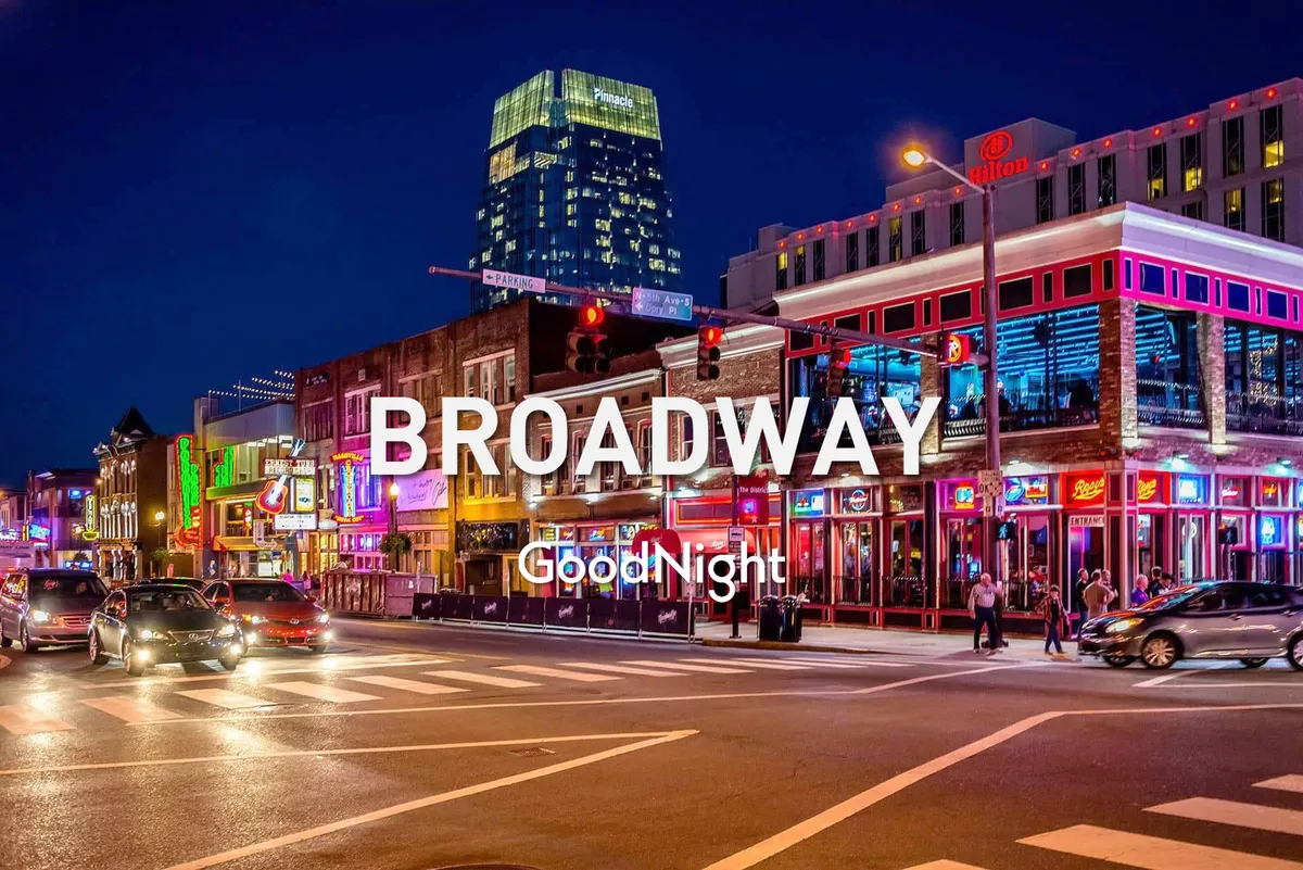 A bustling Berry Hill street scene illuminated by neon signs, with people walking, cars lining the road, and a high-rise building in the background. The area buzzes with activity including dining, live music, shopping, and nightlife, perfectly capturing the neighborhood's lively and vibrant atmosphere.